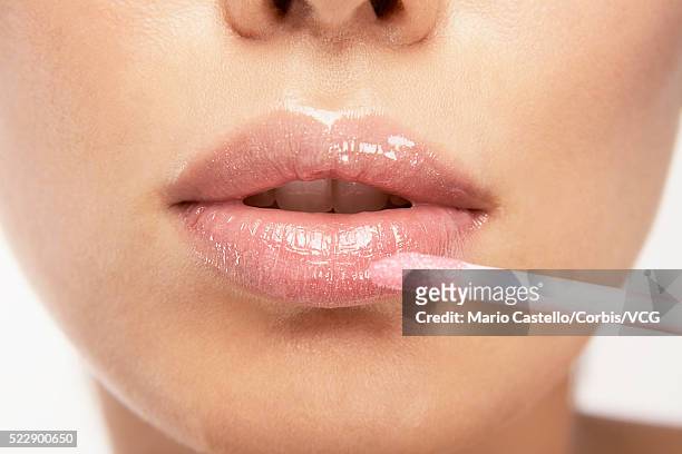 young woman applying pink lipgloss - lipgloss stockfoto's en -beelden