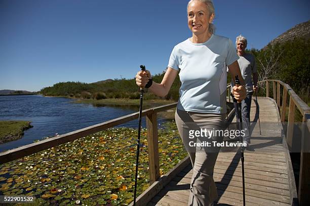 couple nordic walking on bridge - nordic walking stock pictures, royalty-free photos & images