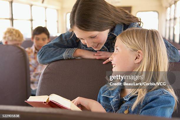 students on school bus looking at book - young girl reading book bus foto e immagini stock