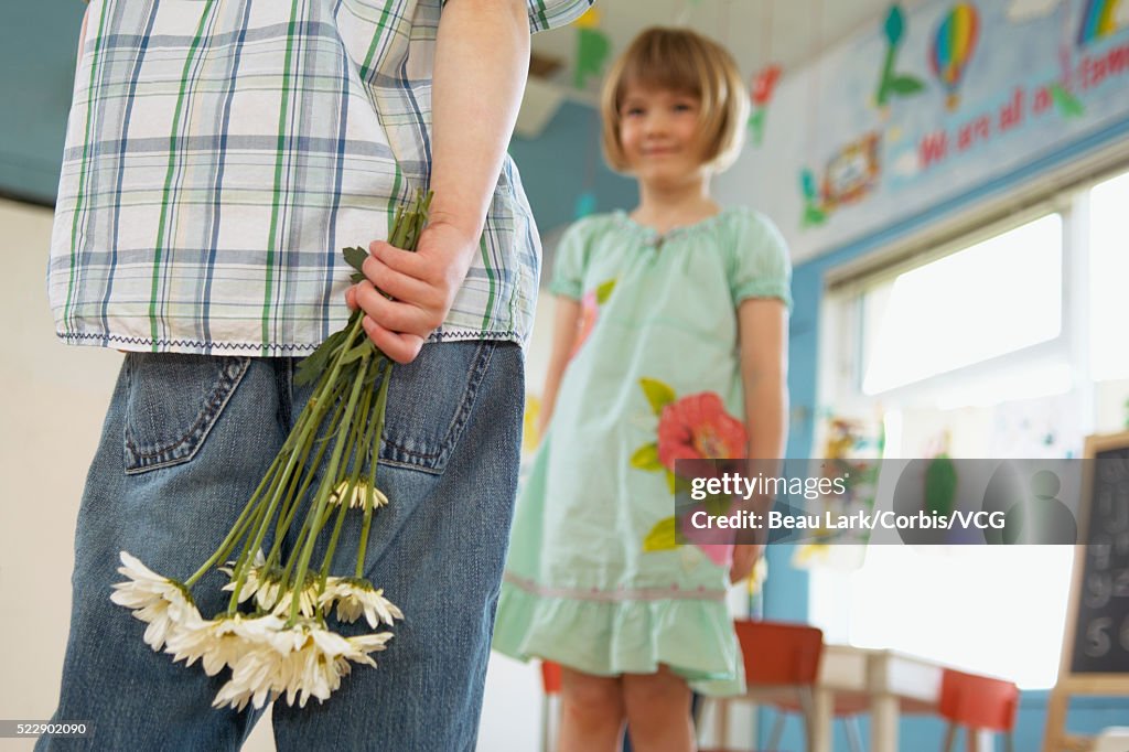 Preschool boy bringing flowers to girl
