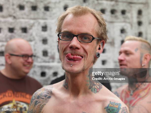 tattooed man showing split tongue - body piercings stock pictures, royalty-free photos & images