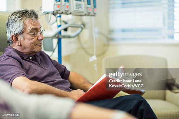 patient reading book in infusion room - chemotherapy stock pictures, royalty-free photos & images