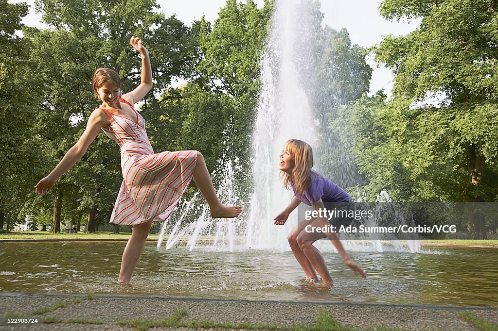 Two friends splashing in a fountain