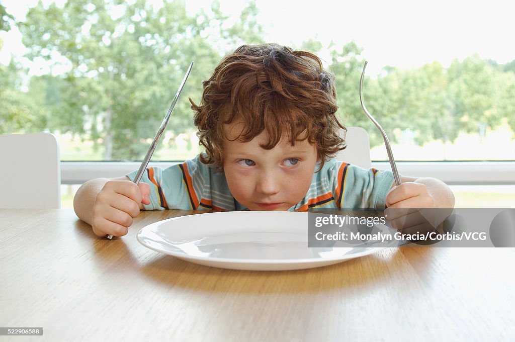 Boy sitting at dinner table waiting for food