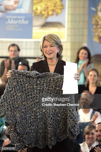 Martha Stewart smiles as she holds up the much publicized poncho she wore when she left prison during a speech to an audience of her employees and...