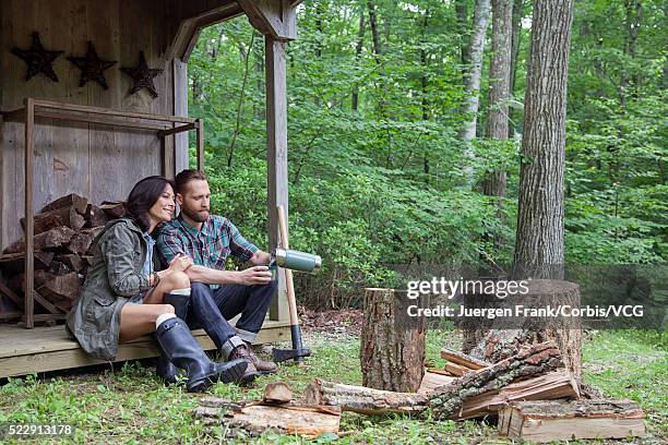 couple sitting on porch of log cabin - frank wood stock pictures, royalty-free photos & images