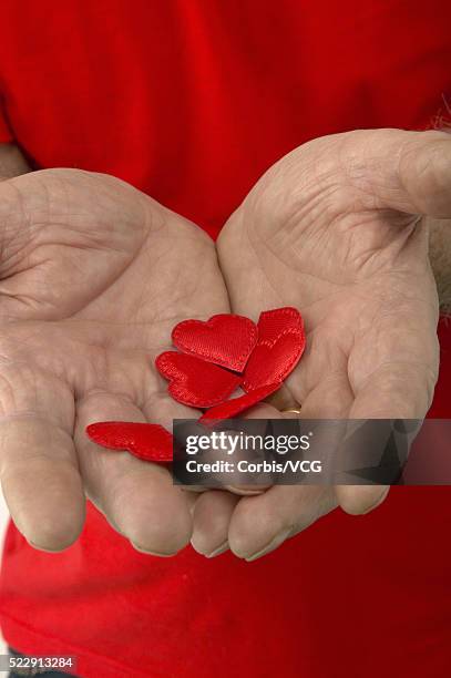 detail view of an aging man holding out some paper hearts - man holding out flowers stock pictures, royalty-free photos & images