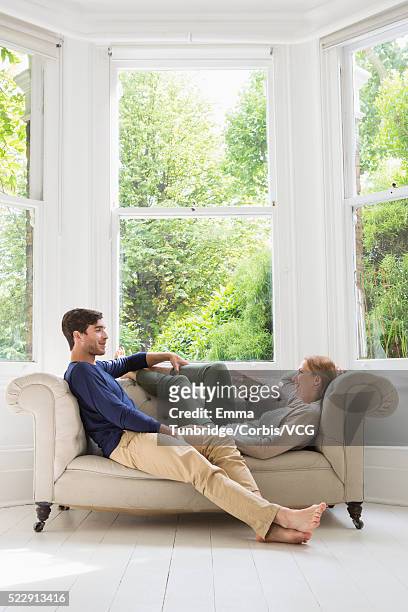 couple relaxing on sofa - couple on sofa stock pictures, royalty-free photos & images