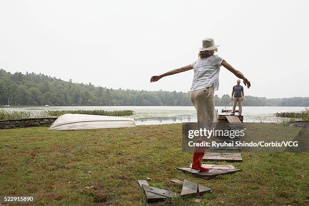 woman wearing rubber boots running by lake - rubber 55 stock-fotos und bilder