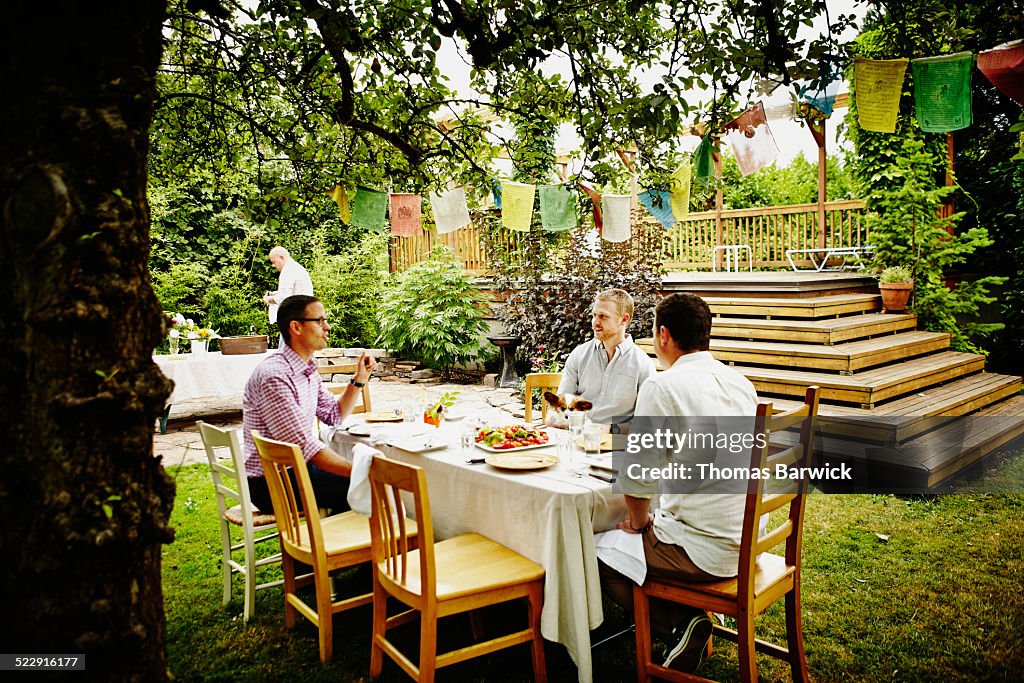 Friends in discussion at table in backyard