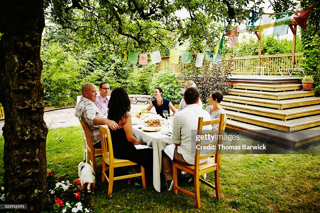 Group of friends having dinner party in backyard