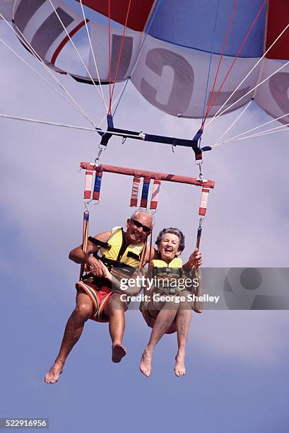 senior couple parasailing - luftsport stock-fotos und bilder