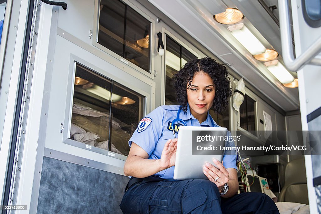 Female paramedic in ambulance using tablet