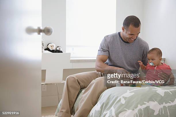 father sitting on the bed with his infant daughter - bettmann corbis stock-fotos und bilder