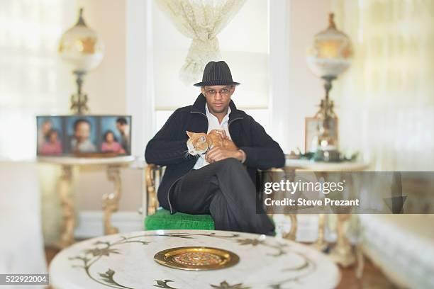 man with cat in living room - man fedora room stock pictures, royalty-free photos & images