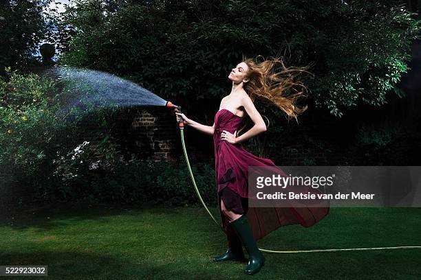 woman watering plants in garden - evening gown stock-fotos und bilder