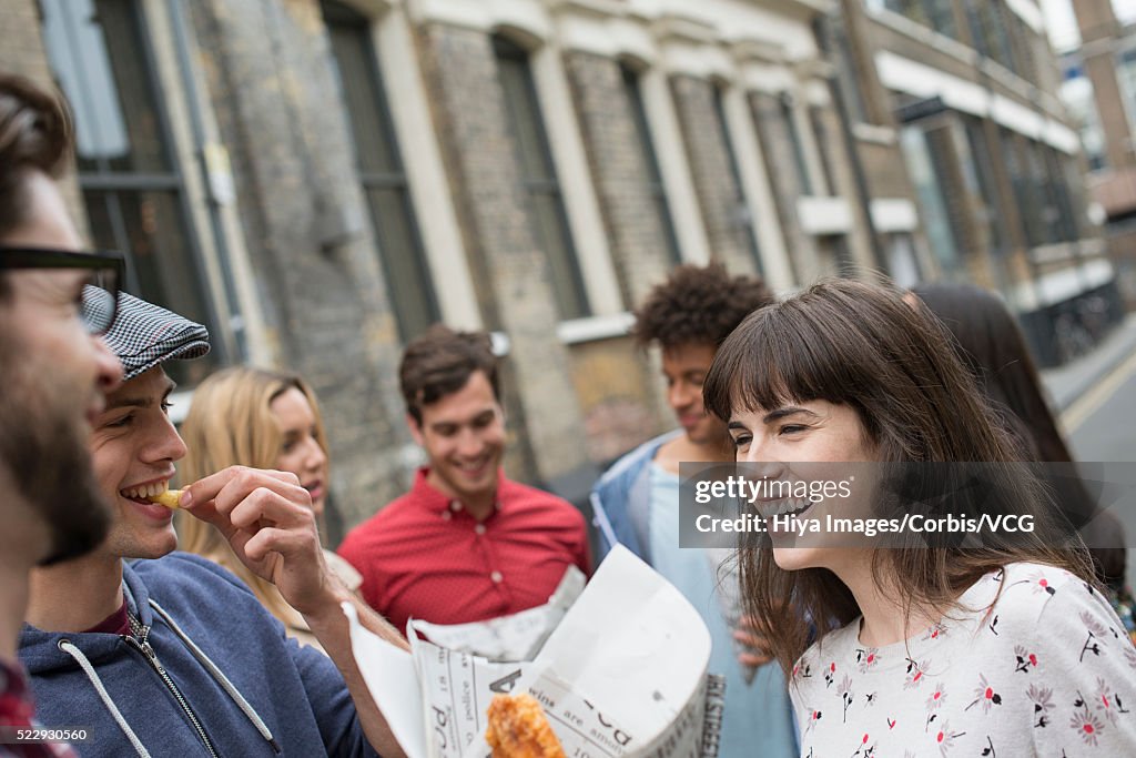 Young women and young men eating fish and chips