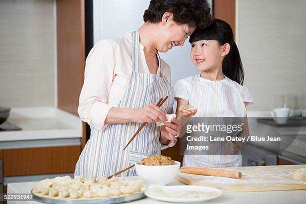 happy grandmother and granddaughter making dumplings - asian granny pics stock-fotos und bilder