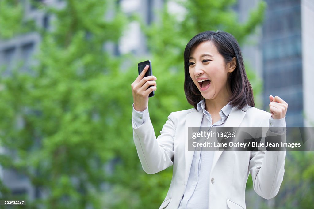 Excited young businesswoman with mobile phone