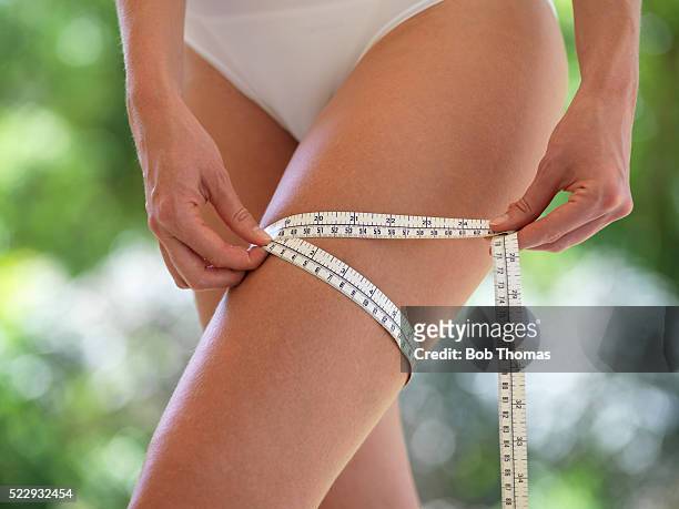 young woman measuring thigh - thigh human leg stock pictures, royalty-free photos & images