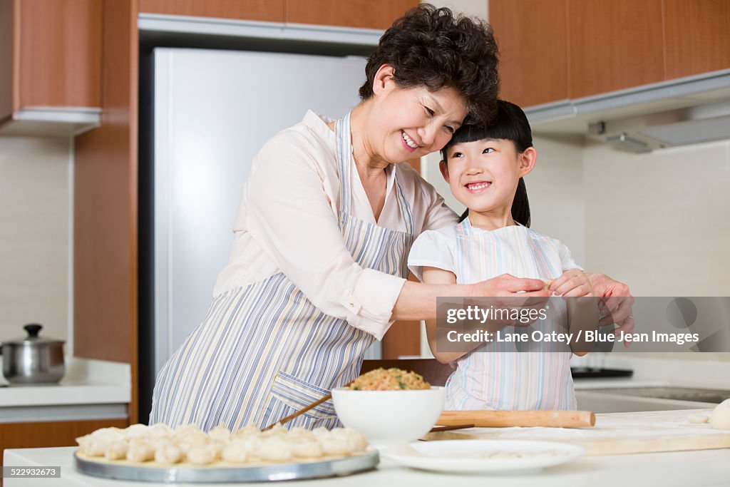 Happy grandmother and granddaughter making dumplings