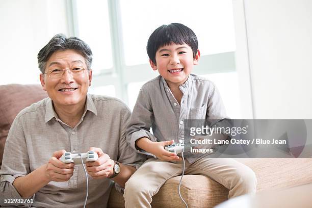 cheerful grandfather and grandson playing video game - neat video stock pictures, royalty-free photos & images