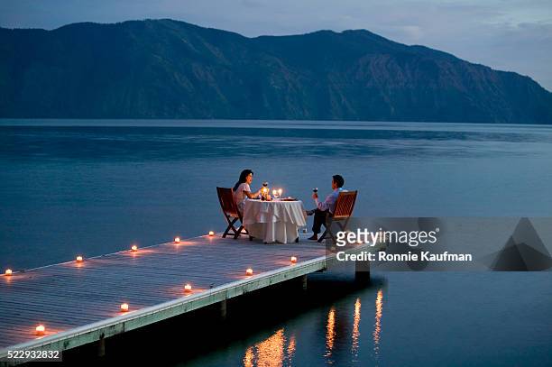 couple having romantic dinner date on pier - warmes abendessen stock-fotos und bilder
