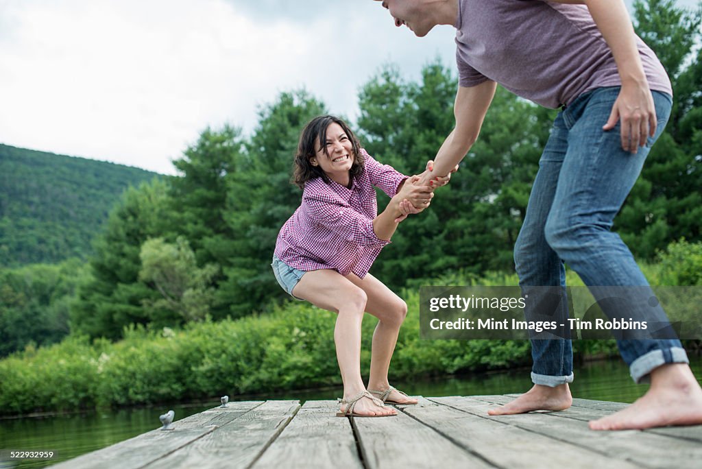 A couple trying to pull each other into the water off a jetty