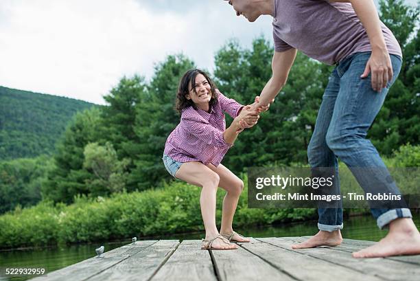 a couple trying to pull each other into the water off a jetty - woman sleep stockfoto's en -beelden