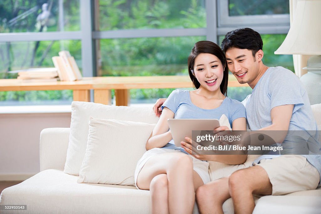Young couple using digital tablet on sofa