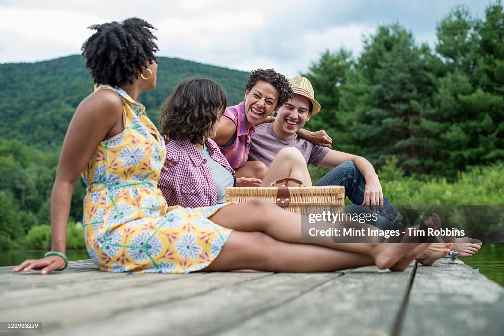 A group of people sitting on a wooden pier overlooking a lake.