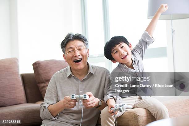 cheerful grandfather and grandson playing video game - 2014 asian games stock-fotos und bilder