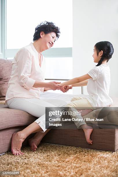 happy grandmother and granddaughter playing in living room - 2014 asian games stock-fotos und bilder