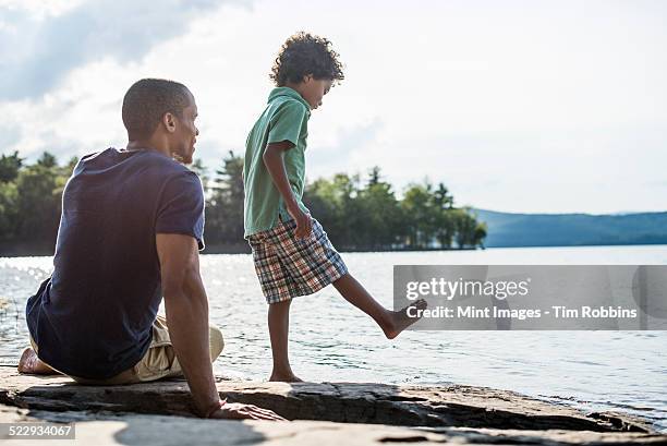 a father and son on a lake shore in summer. - men's water polo stockfoto's en -beelden