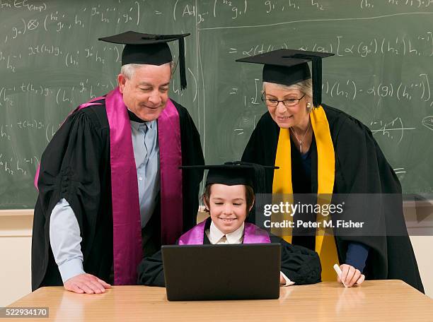 adult graduates and child prodigy in classroom - wonderkind stock-fotos und bilder