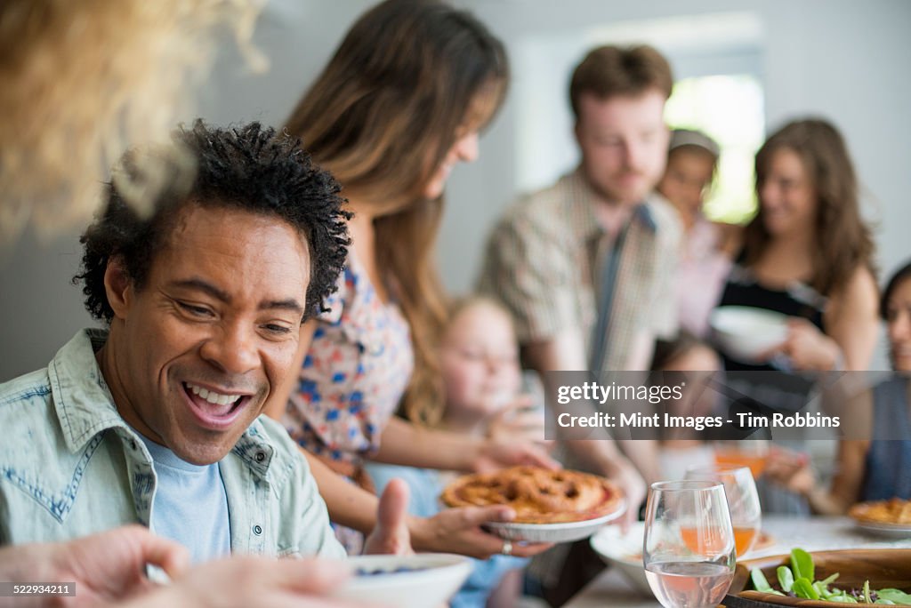 A family gathering for a meal. Adults and children around a table.