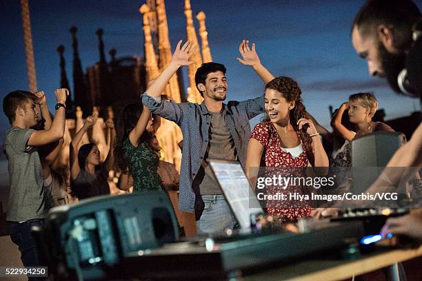 portrait of young couple dancing with disc jockey playing in foreground - rooftop party night stock pictures, royalty-free photos & images