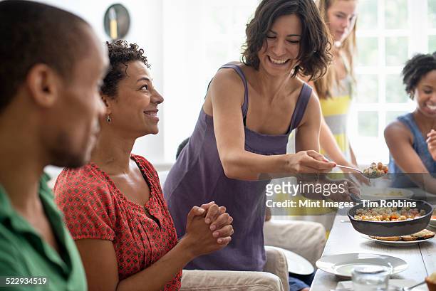 a family gathering, men, women and children around a dining table sharing a meal. - femme bras tendu cuillère photos et images de collection
