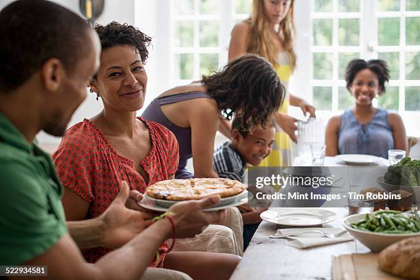 a family gathering, men, women and children around a dining table sharing a meal. - party pies imagens e fotografias de stock