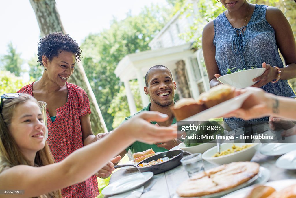 A family gathering, men, women and children around a table in a garden in summer.