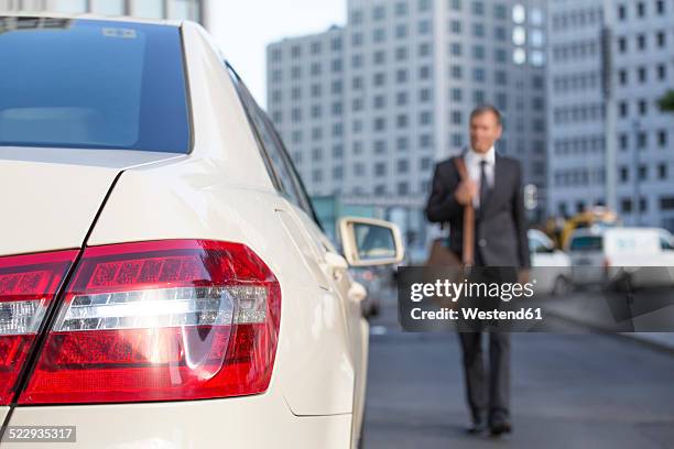 germany, berlin, businessman taking a taxi - rear light car stock-fotos und bilder