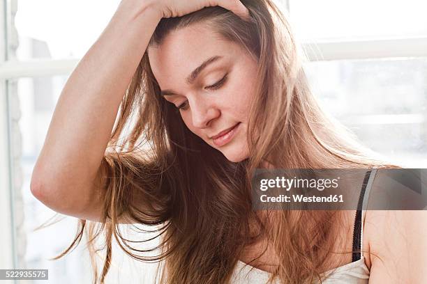 portrait of smiling young woman with hand in her hair - hand in hair imagens e fotografias de stock