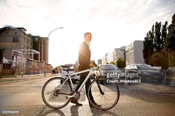 germany, berlin, businessman cycling in the city - bike car stock-fotos und bilder