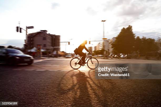 germany, berlin, businessman cycling in the city - city gegenlicht stock-fotos und bilder