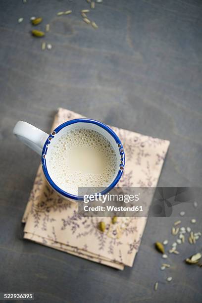 cup of soy rice milk with cardamom and cinnamon on napkin aund wood, elevated view - sojamilch stock-fotos und bilder