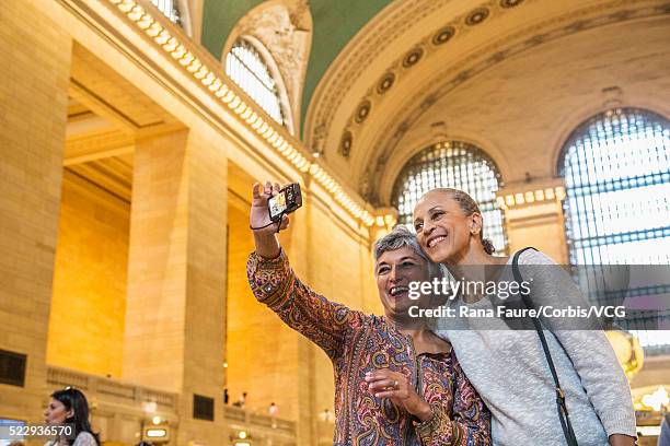 two middle-aged women taking selfie in railroad station - grand central tours stock pictures, royalty-free photos & images