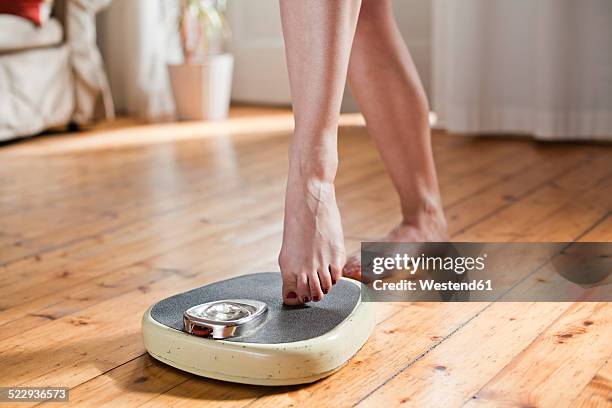 woman testing personal scales, partial view - female feet stock-fotos und bilder