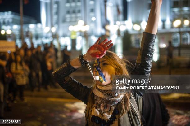 An anti-government protester, her hand and face covered in colorful paint, takes part in a protest in front of the government building in Skopje on...