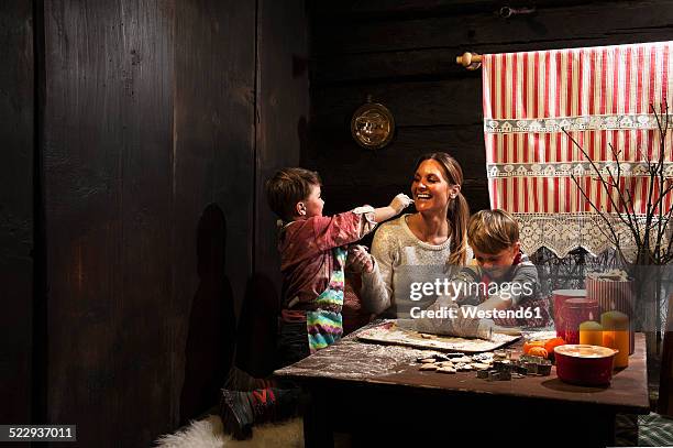 mother and her two little sons baking christmas cookies at advent season - kids advent stock pictures, royalty-free photos & images