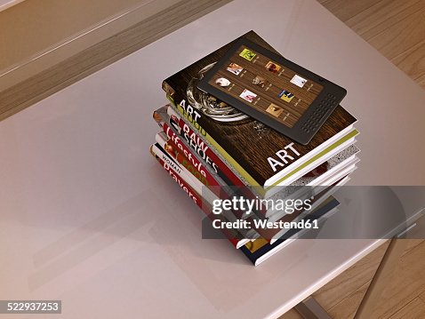 E-reader and stack of books lying on a table, 3D Rendering E-reader and stack of books lying on a table, 3D Rendering